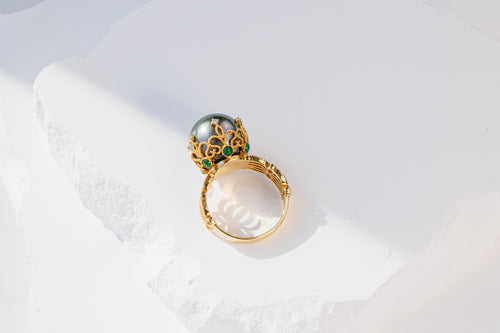 Top view of ring, showing diamond on top of the lace design and emerald highlights