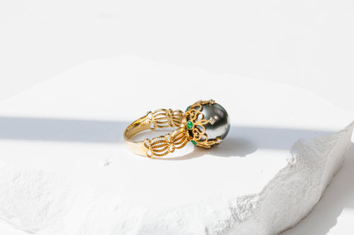 side view of ring laying flat, showcasing lace detail with emerald highlights