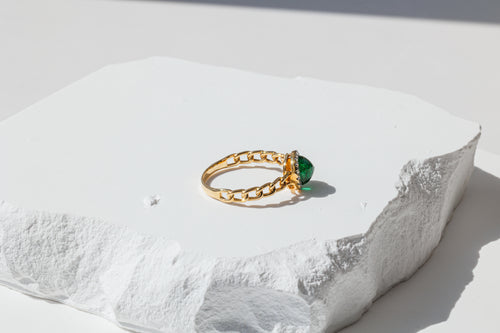 side view of ring, focused on the lace detail and highlights sugarloaf shape of emerlad